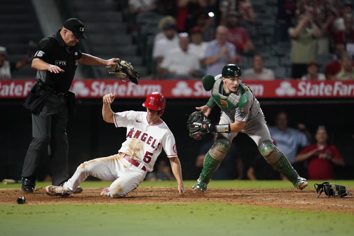 Los Angeles Angels' Matt Duffy (5) scores ahead of a throw to Oakland Athletics catcher Sean Murphy (12) during the eighth inning of a baseball game in Anaheim, Calif., Tuesday, Sept. 27, 2022. Duffy scored off of a single hit by Jo Adell. (AP Photo/Ashley Landis)