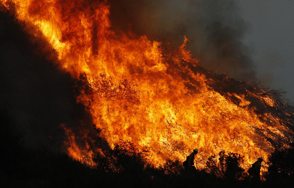 Firefighters are silhouetted against a blazing hillside in Sunland on Tuesday, Sept. 1, 2009.