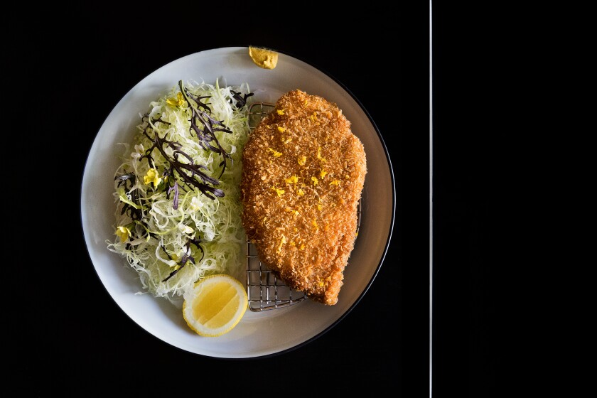 An overhead photo of chicken katsu with salad on a black tabletop.