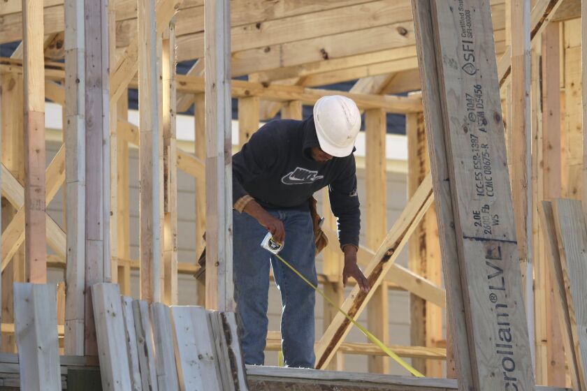 A worker measure before cutting while working on the framing of a house under construction in Coppell, Texas, Monday, Dec. 15, 2014. The Commerce Department reports on U.S. home construction in March Thursday April 16, 2015. (AP Photo/LM Otero)