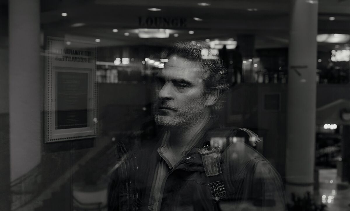 A scene from the film "C'mon C'mon," with Joaquin Phoenix being reflected in a glass elevator.