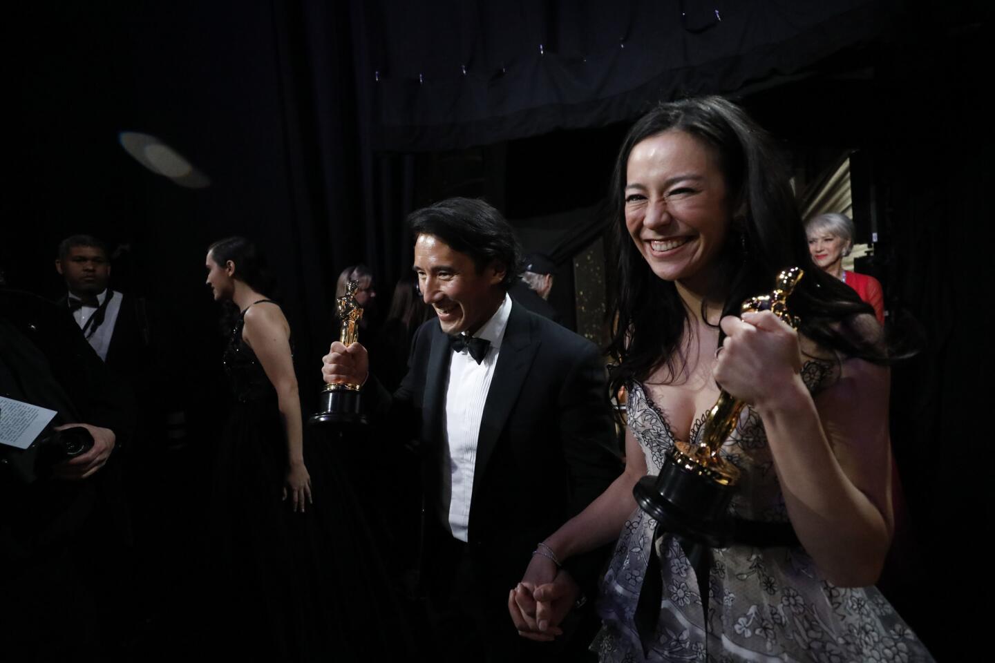 Jimmy Chin and Elizabeth Chai Vasarhelyi, co-directors of the feature documentary "Free Solo," carry their Oscars offstage at the 91st Academy Awards.
