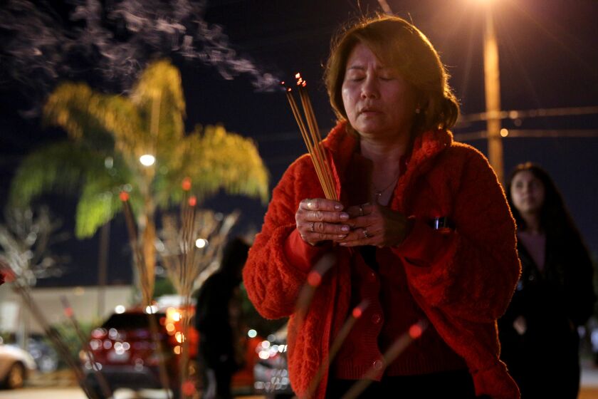 Annie Le, 54 of El Monte, prays for the 11 shooting victims, at the memorial site in front of Star Ballroom Dance Studio in Monterey Park on Thursday, Jan. 26, 2023.