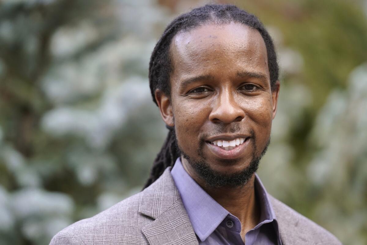 A closeup of a smiling man in a button-down shirt and a suit jacket.