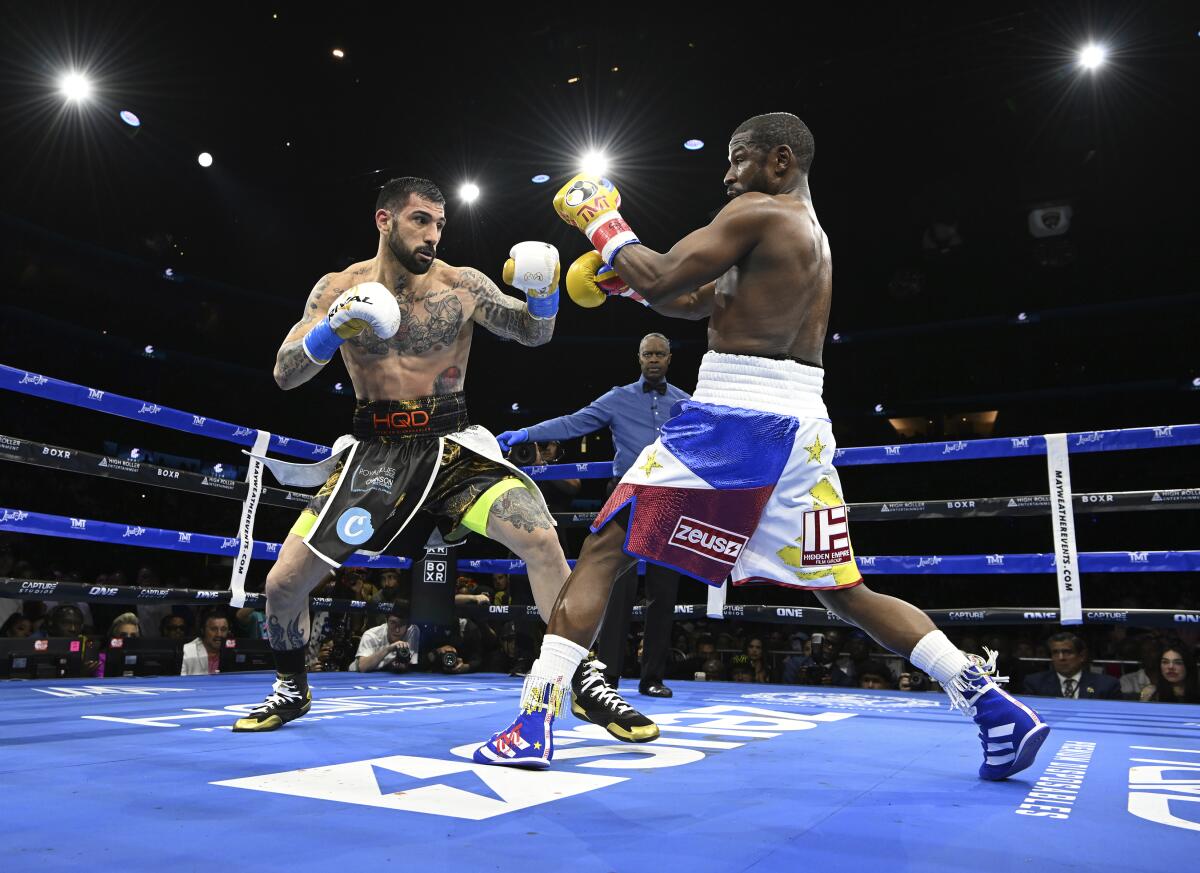 John Gotti III and Floyd Mayweather boxing in a ring as referee Kenny Bayless watches