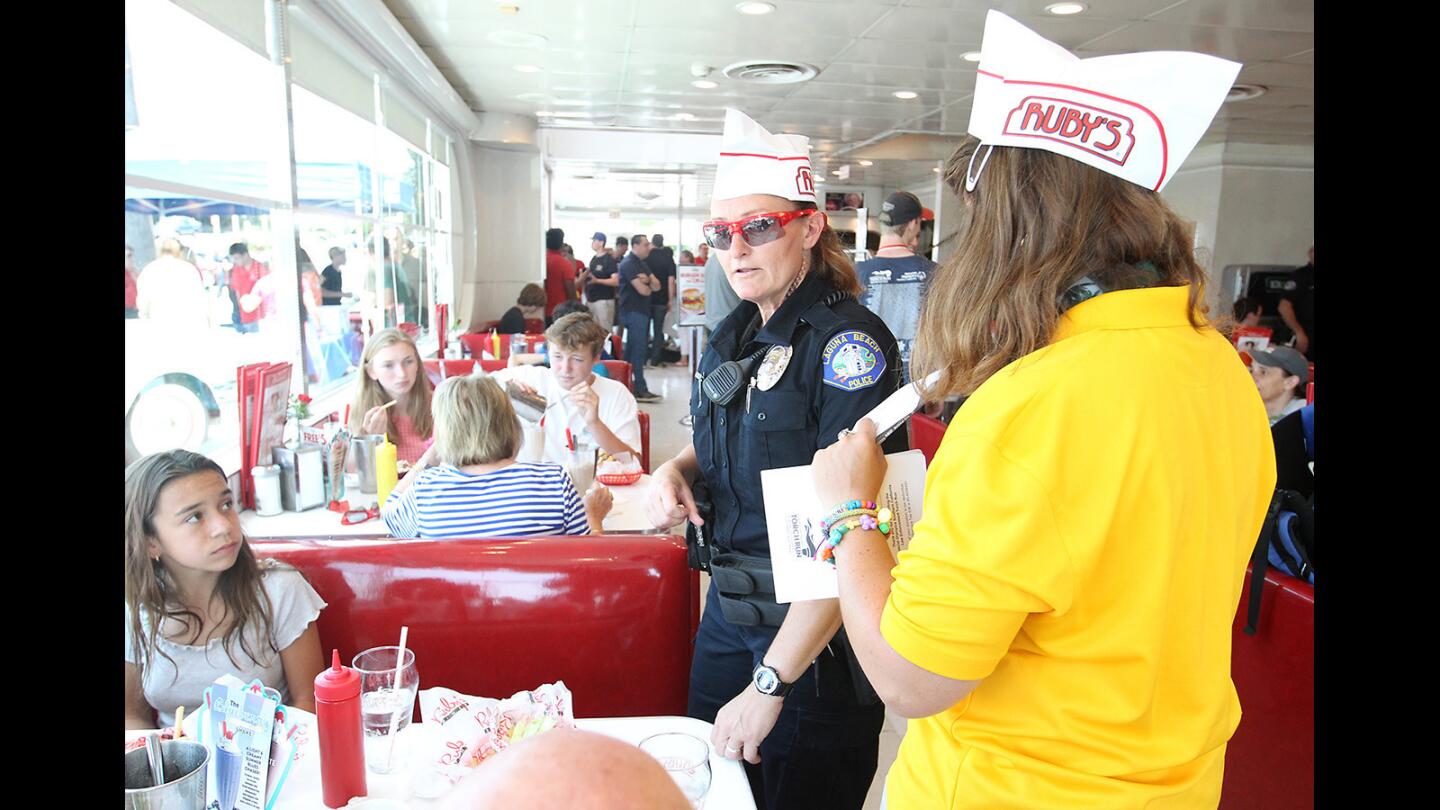 Laguna Beach Officer Joy Butterfield and Sara Thiel, of special olympics, from left, greet customers during the Special Olympics Tip-a-Cop fundraiser at Ruby's Diner in Laguna Beach on Saturday.