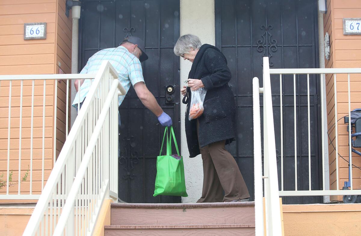 Driver Jason Pastore from Sally's Fund delivers a bag of groceries to a resident of the Vista Aliso senior apartments in Laguna Beach on Thursday.