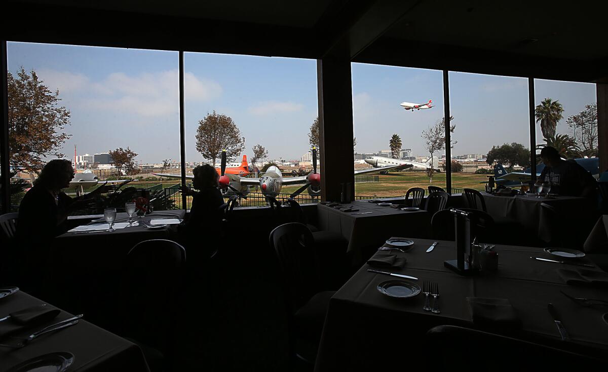 Diners at the Proud Bird restaurant take in the view of vintage aircraft as a jet approaches for landing at LAX in the background.