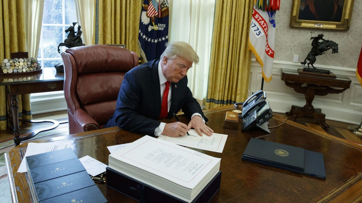 President Trump signs the tax bill in the Oval Office of the White House on Dec. 22 in Washington.