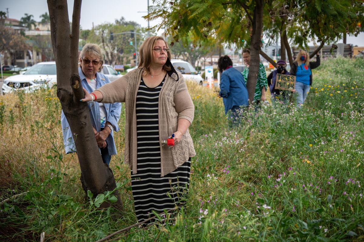 Barbara Sessions (right) and Betty McMillen stand in protest next to Jacaranda trees slated to be cut down in Lakeside.