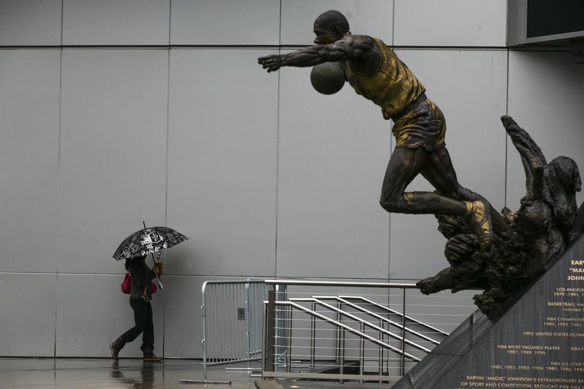 Rain falls on a statue of Magic Johnson as fans walk along Star Plaza hours before the L.A. Clippers and the Miami Heat play at Staples Center.