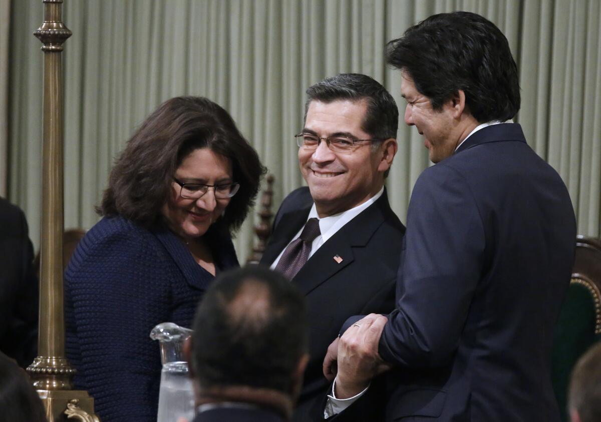 Xavier Becerra, center, shown with his wife Carolina Reyes, left, is congratulated by Senate President Pro Tem Kevin de León (D-Los Angeles) after being sworn in by Gov. Jerry Brown as the attorney general of California on Tuesday.
