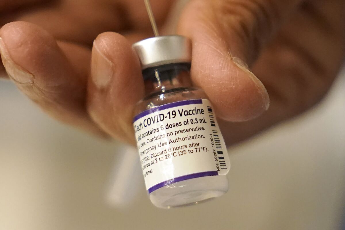 A dose of COVID-19 vaccine is transferred into a syringe. 