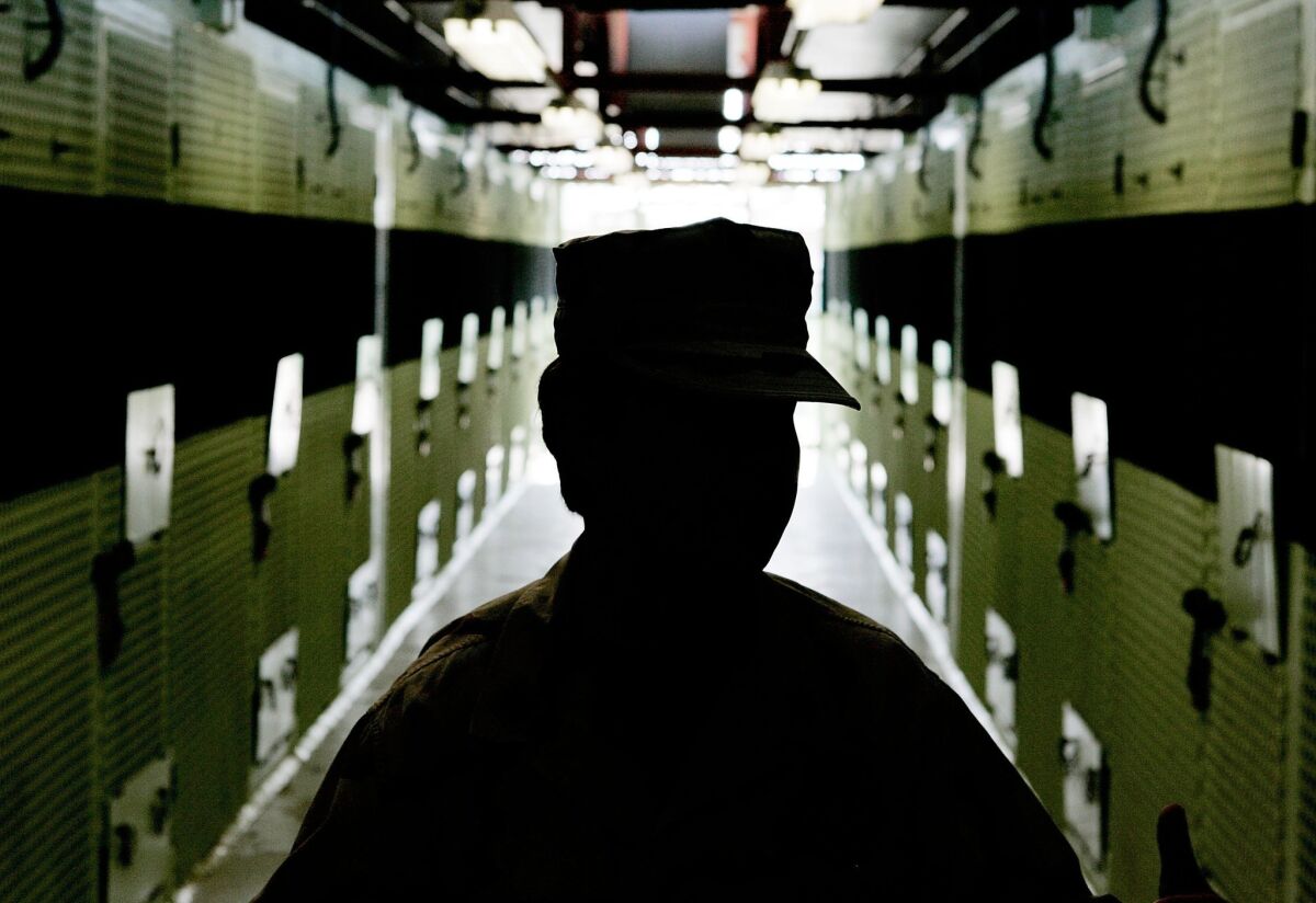 A member of the military is silhouetted while standing inside a cell block at Guantanamo Bay, Cuba. A man still being held in the facility will publish a memoir next year.
