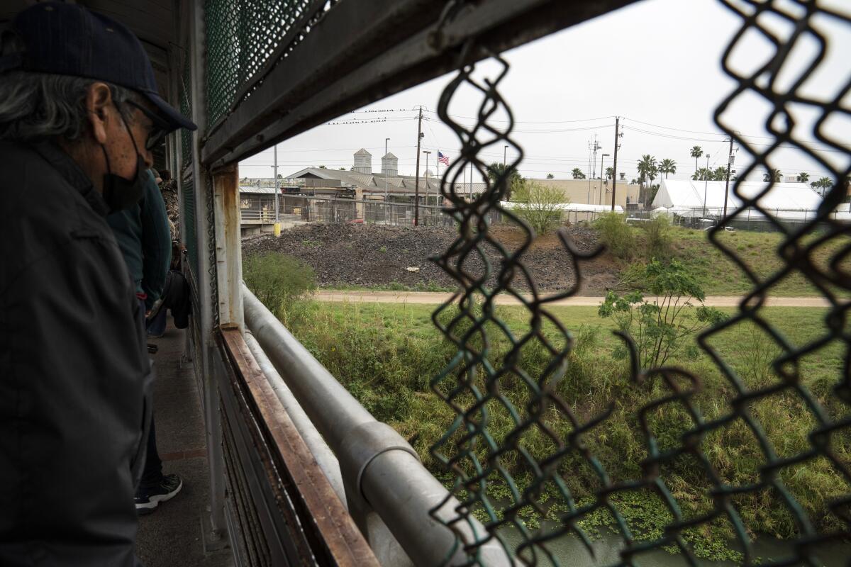 A man looks through a hole in the fence in the Gateway International Bridge 