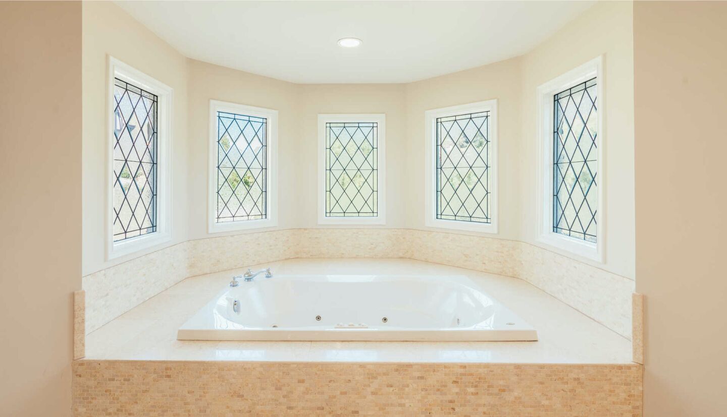 Mullioned windows in an alcove holding a spa tub.