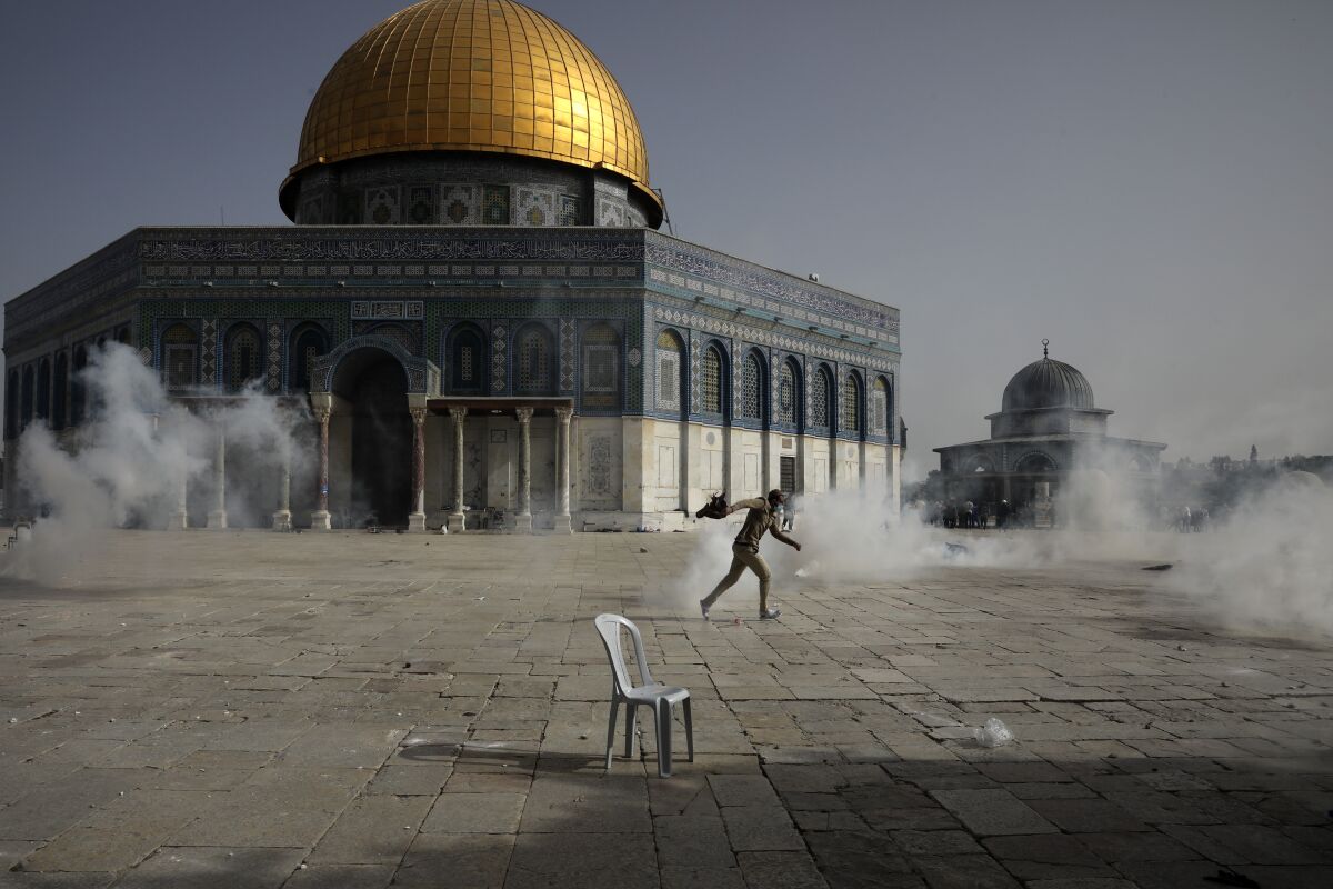 FILE - A Palestinian man runs away from tear gas during clashes with Israeli security forces in front of the Dome of the Rock Mosque at the Al Aqsa Mosque compound in Jerusalem's Old City Monday, May 10, 2021. Israel’s attorney general has upheld the Shin Bet security agency’s use of mobile-phone tracking technology to monitor and threaten Palestinian protesters at Jerusalem’s most sensitive holy site last year. The decision, which came on Tuesday, Feb. 1, 2022 drew harsh criticism from the civil rights group that challenged the use of the technology. The group warned that it would have a “chilling effect” on the country's Arab minority. (AP Photo/Mahmoud Illean)