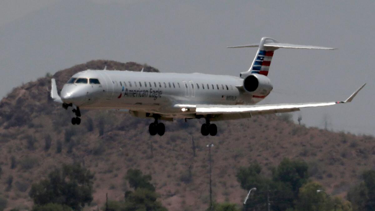 An American Eagle jet flies through heat ripples as it lands at Sky Harbor International Airport in Phoenix. Some employees of Envoy Air, an American Airlines subsidiary that operates under the American Eagle brand, say they must turn to public assistance to make ends meet.