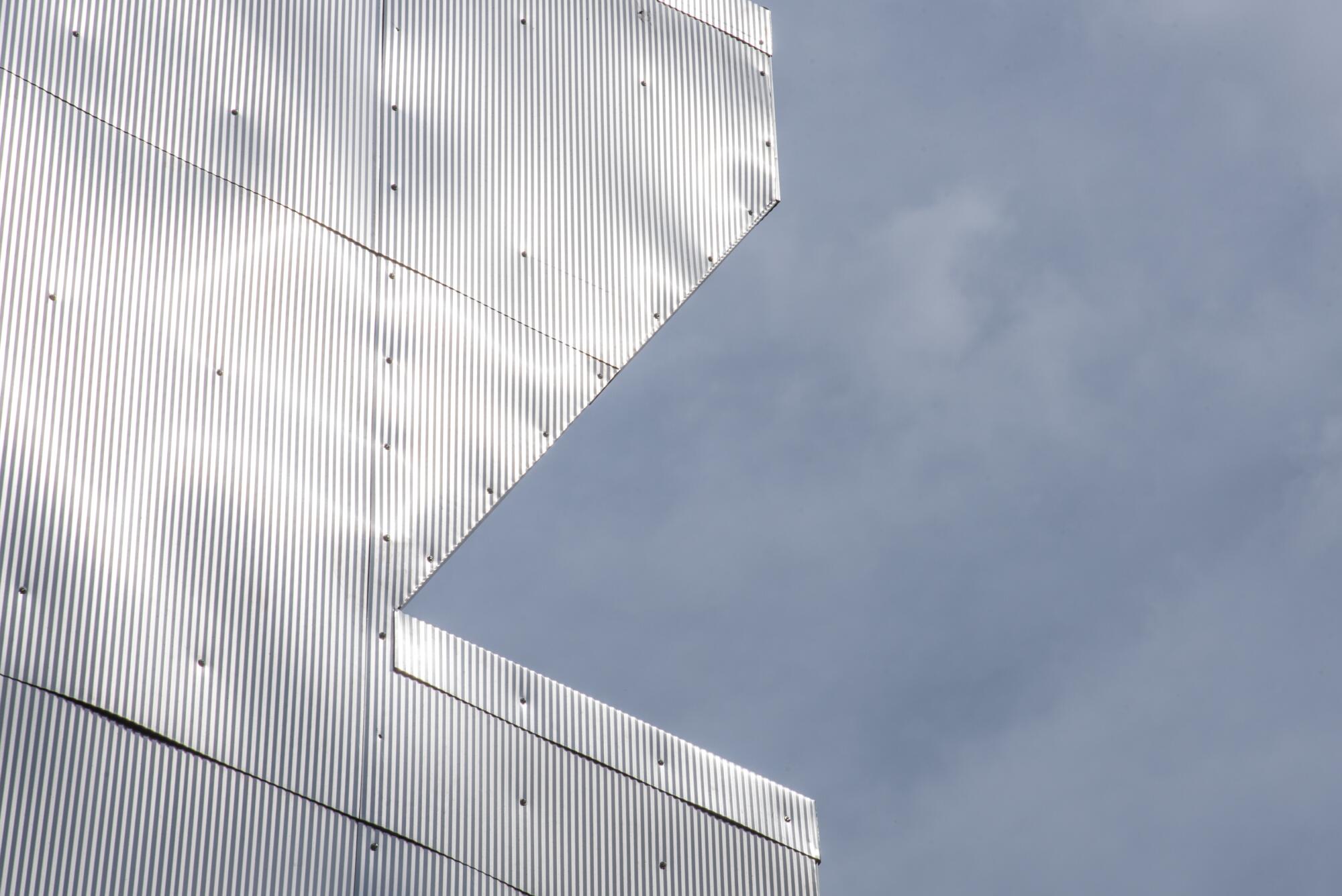 Details of the corrugated metal siding of the Aluminaire House against a blue sky.