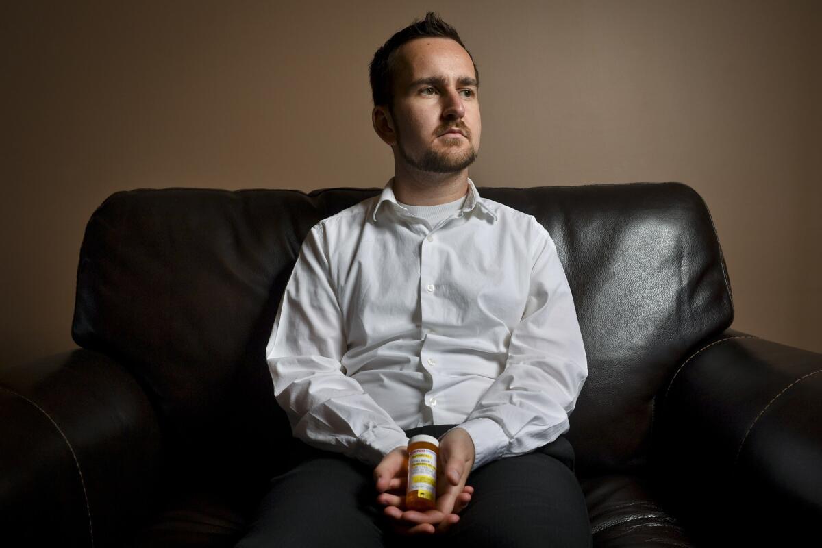 Stoll holds a vial of Tramadol, one of the medications he takes to treat severe back pain. He had to stop using pot to remain in good standing with the Church of Jesus Christ of Latter-day Saints and get married in the temple.