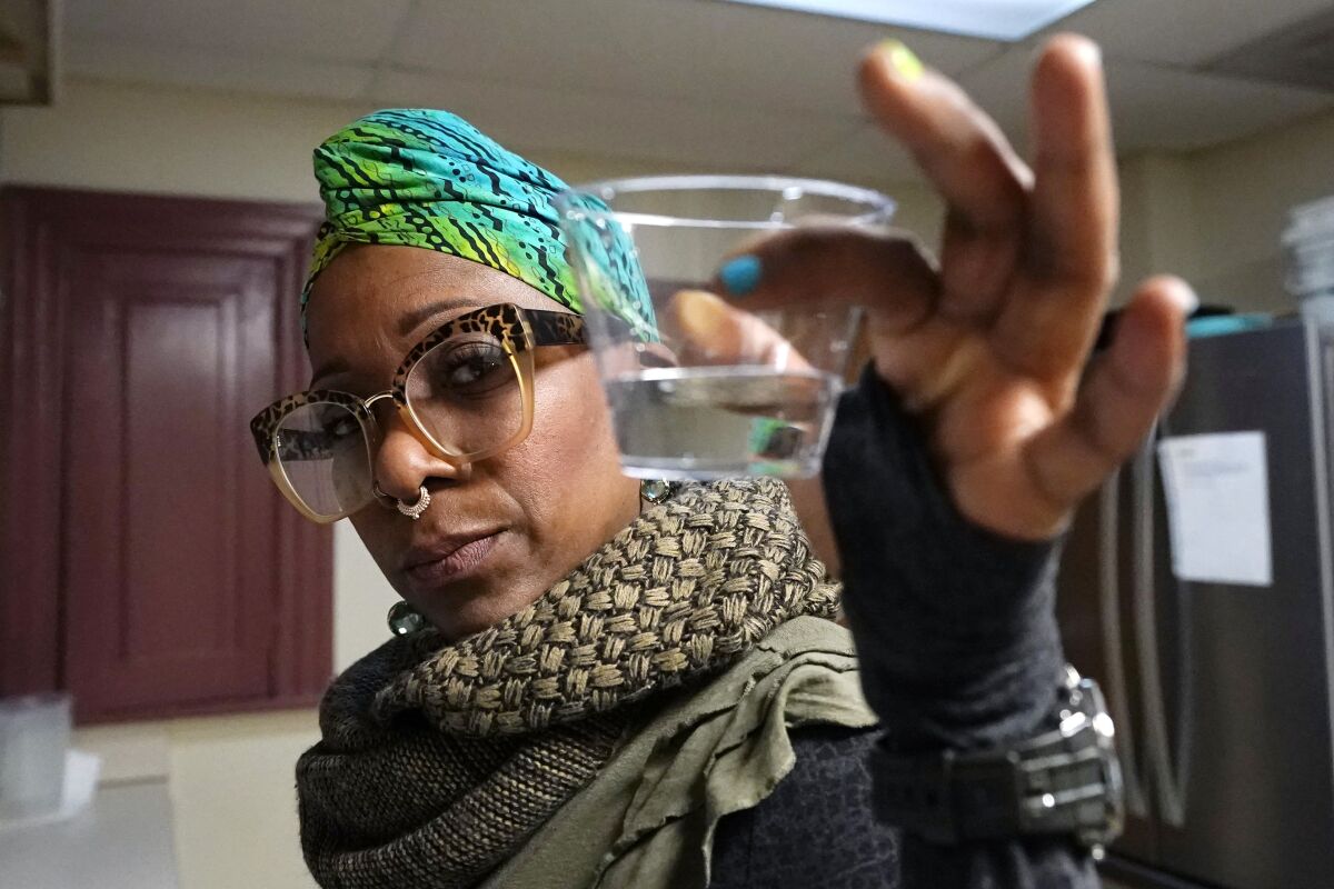 A woman holds a sampling of tap water in Flint, Mich. 