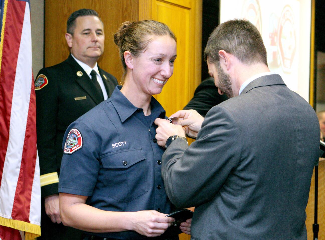 With Glendale Fire Dept. Chief Greg Fish looking on at rear, David Scott pins the badge on his wife and new Glendale firefighter Leslie Scott, at the Class of 2016 Burbank and Glendale Fire Departments Firefighter Recruit Academy graduation ceremony, at the Burbank Fire Dept. Training Center in Burbank, on Friday, Dec. 16, 2016. Glendale F.D. had 13 graduates and Burbank had 8 graduates.