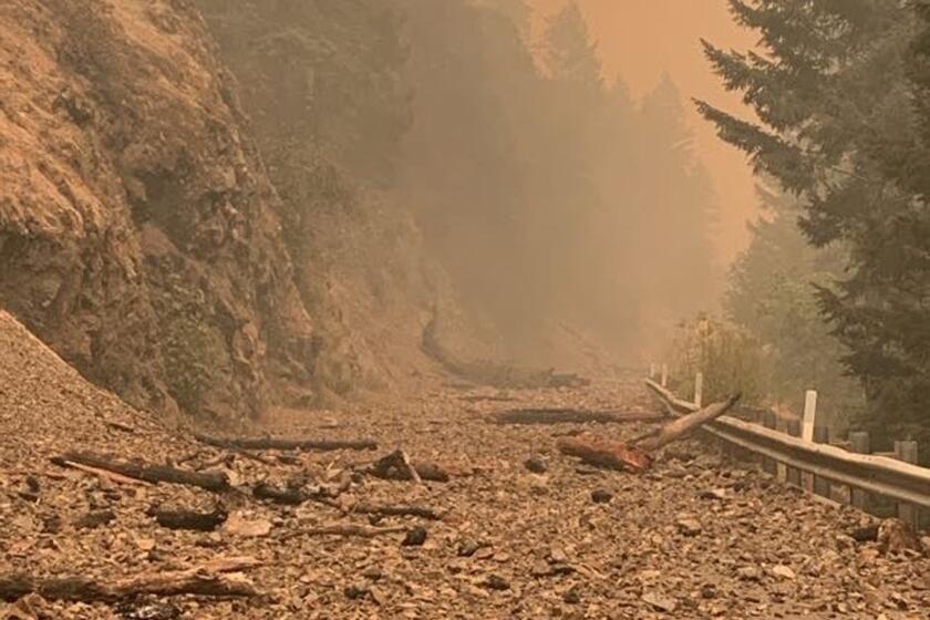 In this photo provided by Caltrans, smoke and damage from the Smith River Complex Fire is seen on the closed U.S. Route 199 in Gasquet, Calif., on Thursday, Aug. 17, 2023. (Caltrans via AP)