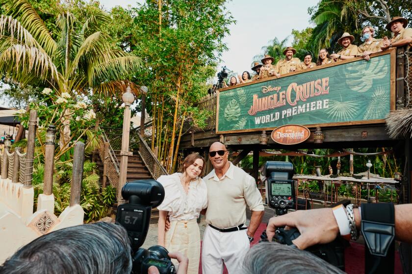 Anaheim, CA - 7/24/21: Emily Blunt and Dwayne Johnson exit the Jungle Cruise ride and pose for photographers on the red carpet for the premier of the new film Disney's Jungle Cruise while Disney cast members of the Jungle Cruise ride watch. Saturday, July 24, 2021 in Disneyland. (PHOTOGRAPH BY ADAM AMENGUAL / FOR THE TIMES)