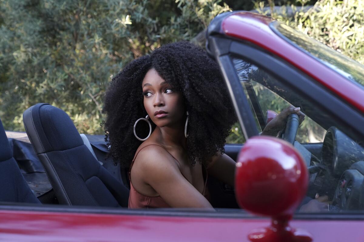 A woman in the driver's seat of a convertible looks back over her shoulder.