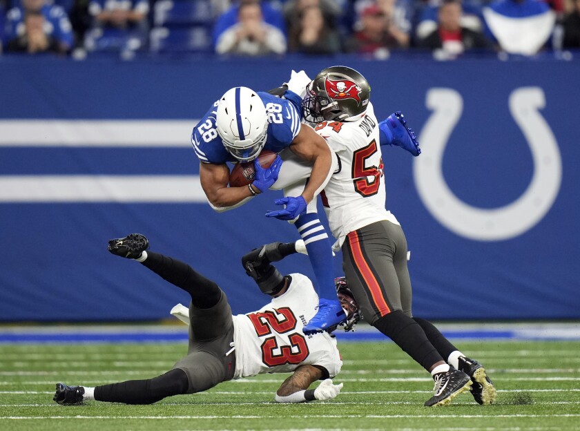 Indianapolis Colts' Jonathan Taylor (28) is tackled by Tampa Bay Buccaneers' Sean Murphy-Bunting (23) and Lavonte David (54) during the first half of an NFL football game, Sunday, Nov. 28, 2021, in Indianapolis. (AP Photo/AJ Mast)
