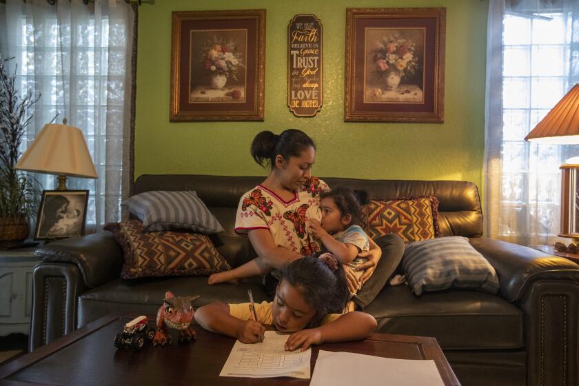 PANORAMA CITY, CA - OCTOBER 14, 2021: Mireya Tecpaxohitl Gonzalez, 32, nurses son Hoshea Gonzalez, 3, as her daughter Hadassah Martinez, 7, a 1st grader, does math homework at their home in Panorama City. Mireya received the COVID-19 vaccine and has opted to not wean her children so she can pass on COVID-19 antibodies to them. (Mel Melcon / Los Angeles Times)