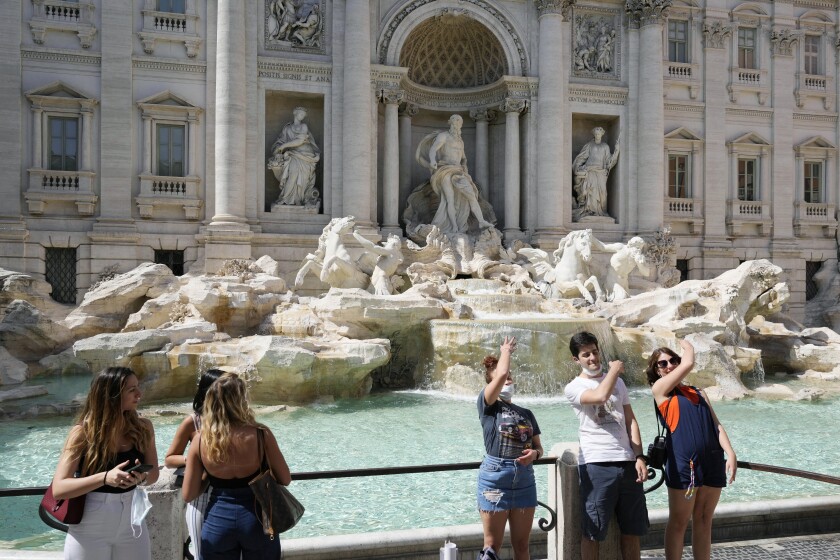 People stand in front of a classical fountain.