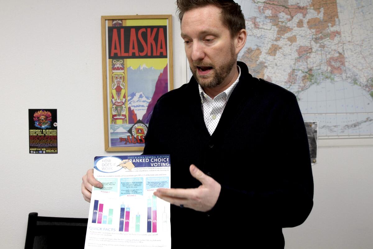 Former Alaska lawmaker Jason Grenn holds an Alaska Division of Elections brochure 