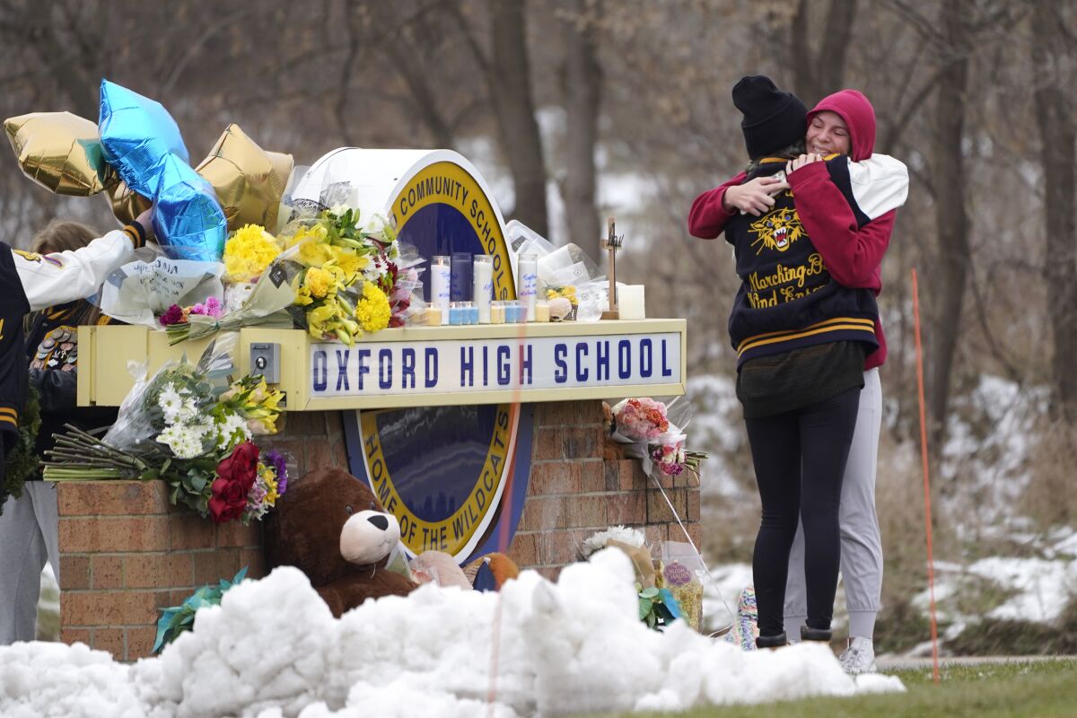 Students hug at a memorial at Oxford High School in Oxford, Mich., Wednesday, Dec. 1, 2021. Authorities say a 15-year-old sophomore opened fire at Oxford High School, killing four students and wounding seven other people on Tuesday. (AP Photo/Paul Sancya)