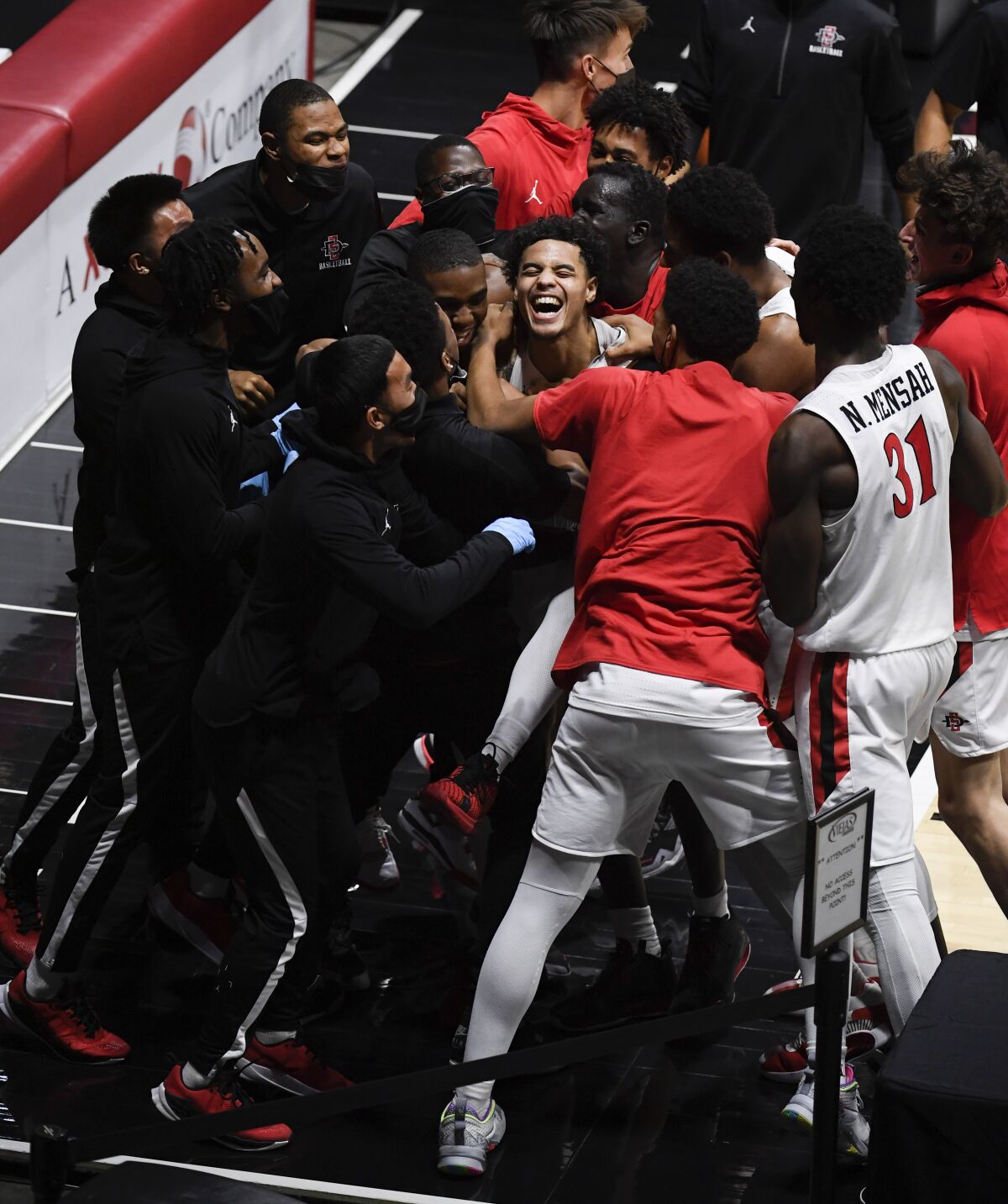 SDSU guard Trey Pulliam (center) is congratulated by teammates after scoring the winning basket against Nevada.