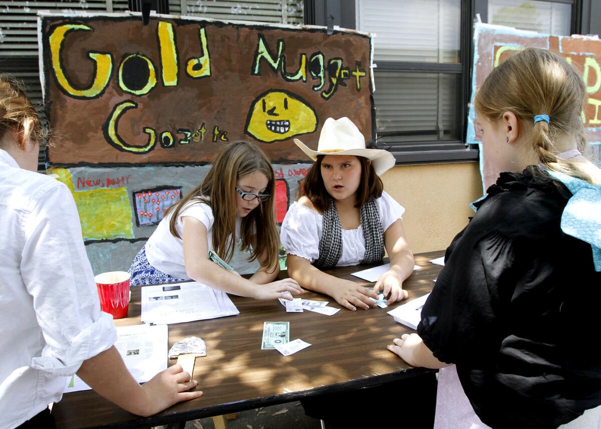 Newspaper editors Shannon West, left center, and Olivia de Fabry, center right, make money selling the Gold Nugget Gazette to students like Nova McNally, right, during the Roosevelt Elementary School Gold Rush Day at the Burbank school on Friday, May 23, 2014. All 4th graders participated in the event.
