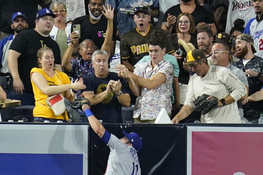 Los Angeles Dodgers left fielder AJ Pollock makes the catch at the wall, competing against fans for the ball, for the out on San Diego Padres' Manny Machado during the fourth inning of a baseball game Tuesday, Aug. 24, 2021, in San Diego. (AP Photo/Gregory Bull)
