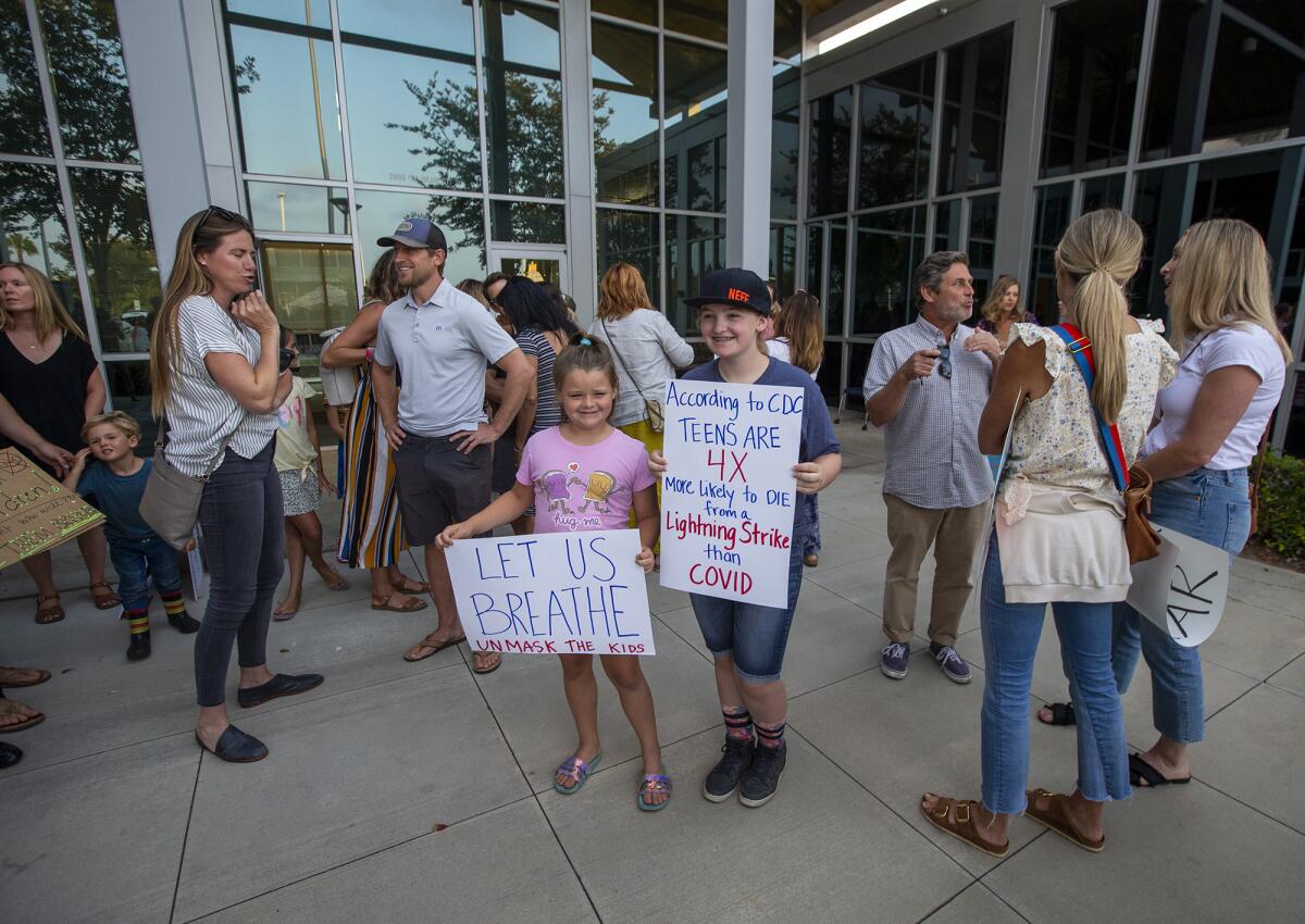 Children hold signs during an Aug. 17  "Let Them Breathe" rally outside the Newport-Mesa Unified School District office.