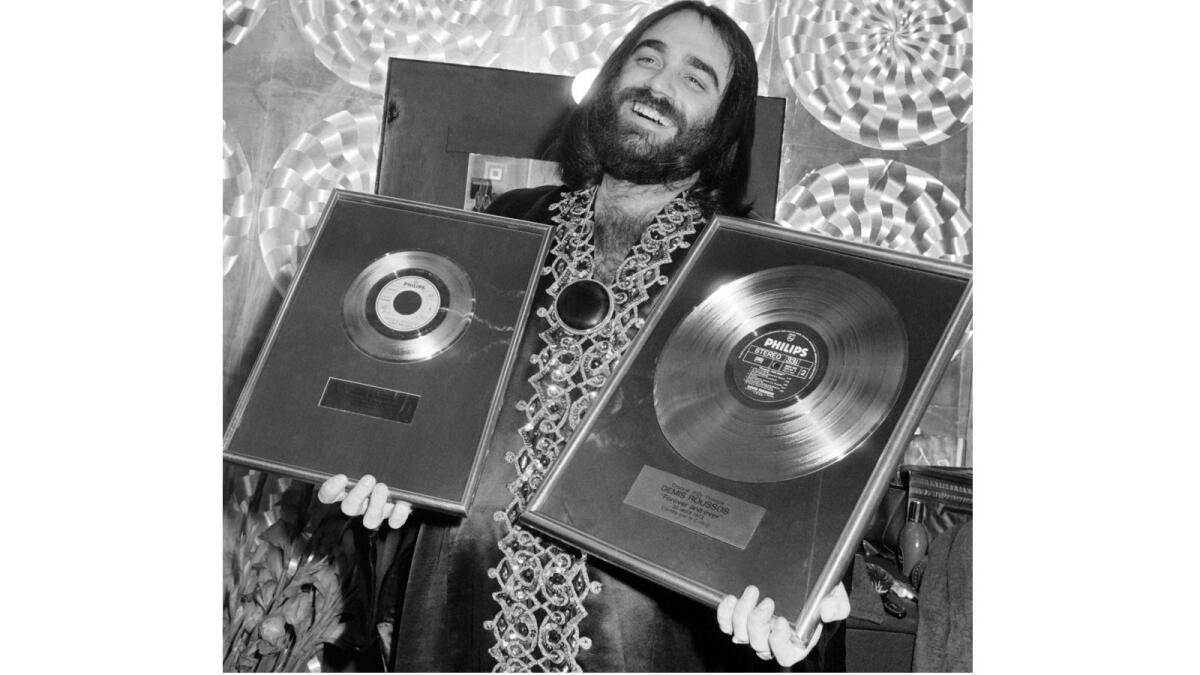 Demis Roussos holds gold records he received for his single and album "Forever and Ever" at a ceremony in Paris on Dec. 4, 1973.