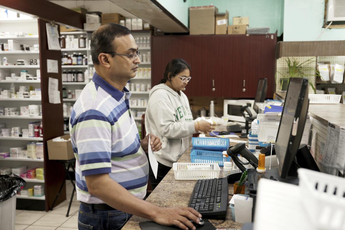 Prakash Patel (primer plano), dueño y farmaceuta, trabaja en Bert's Pharmacy en Elizabeth, 