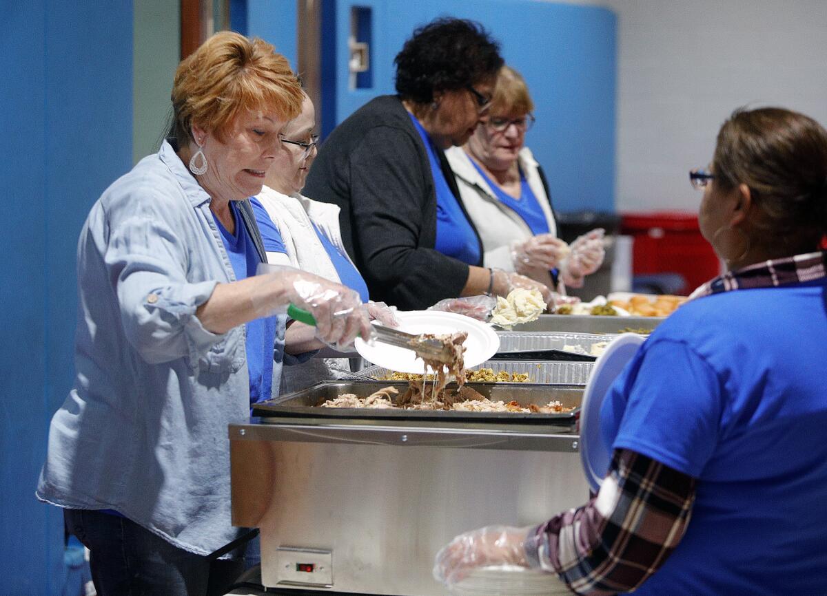 Diana Janow and other volunteers from the California Insurance Guarantee Association prepare plates of food at the annual Thanksgiving meal served at the Glendale Salvation Army on Wednesday, Nov. 27, 2019.