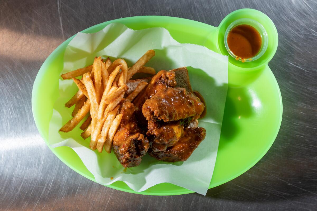 An order of wings slathered in Boss Sauce, with a side fries and the traditional piece of bread (under the wings), at CJ's Wings