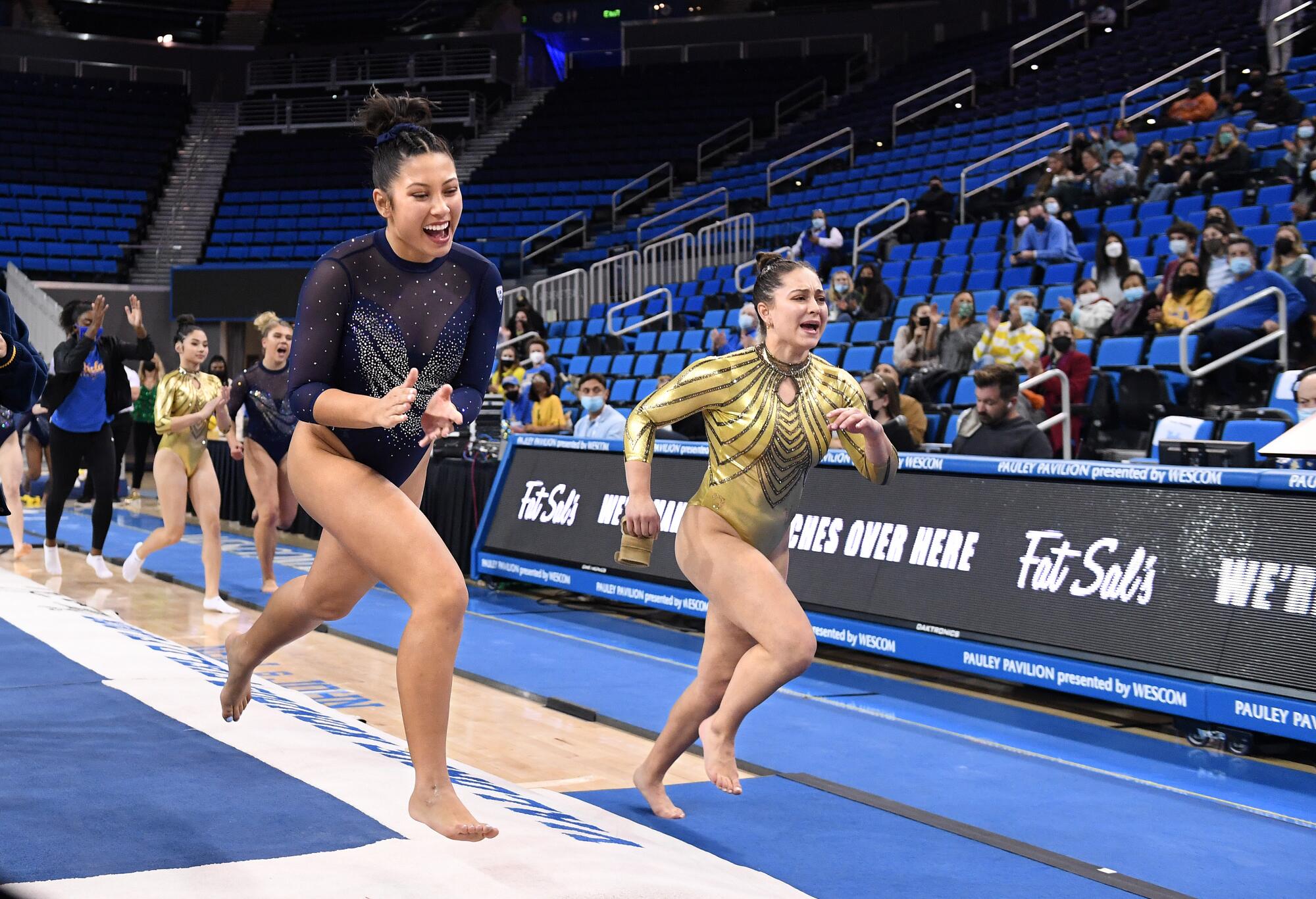 UCLA gymnasts run next to the seating area after competing on the vault.