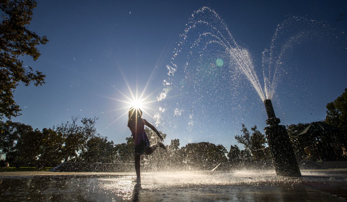 A child plays in a splash pool Tuesday amid a heat wave at Mile Square Regional Park.