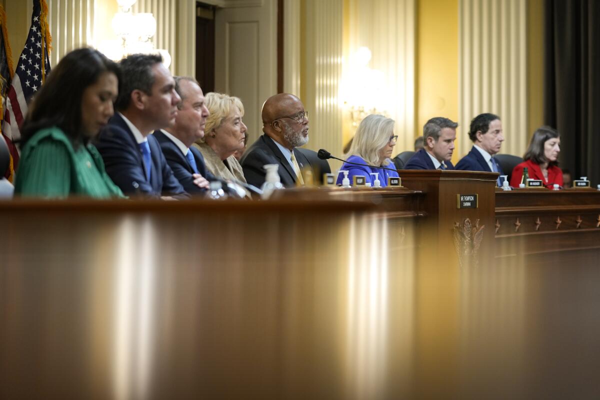 Members of the House Jan. 6 committee sit behind a wood panel.