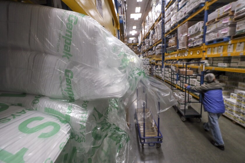A customer walks past styrofoam meat plates stacked high in a warehouse-like aisle at the Restaurant Depot in Barrio Logan