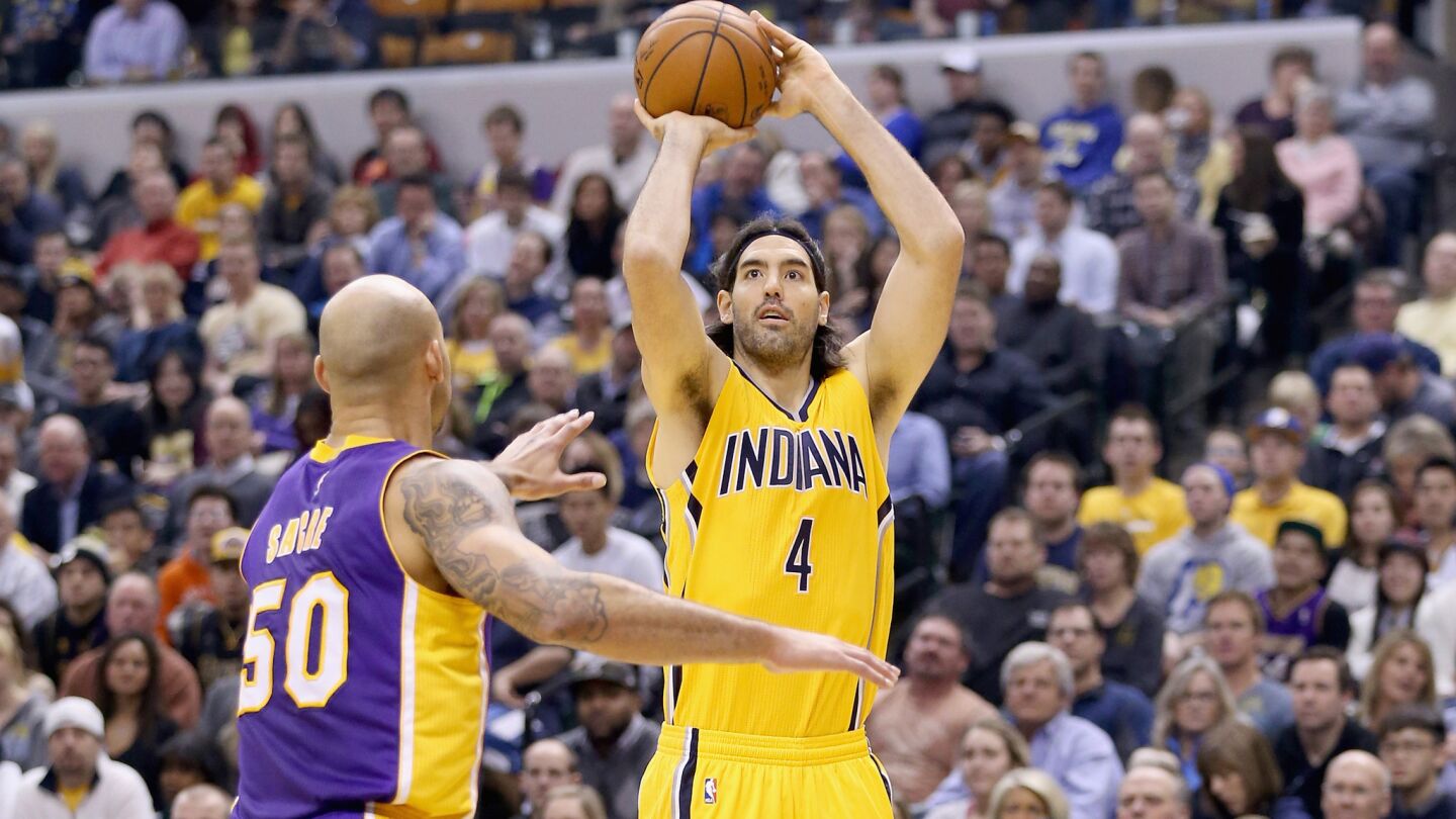 Indiana Pacers guard Luis Scola, right, shoots over Lakers center Robert Sacre during the first half of Monday's game.