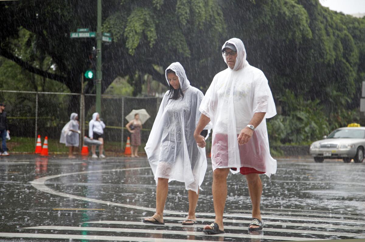 Tourists cope with wet weather in Waikiki in Honolulu Sunday.