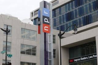 An NPR sign on a column outside gray buildings
