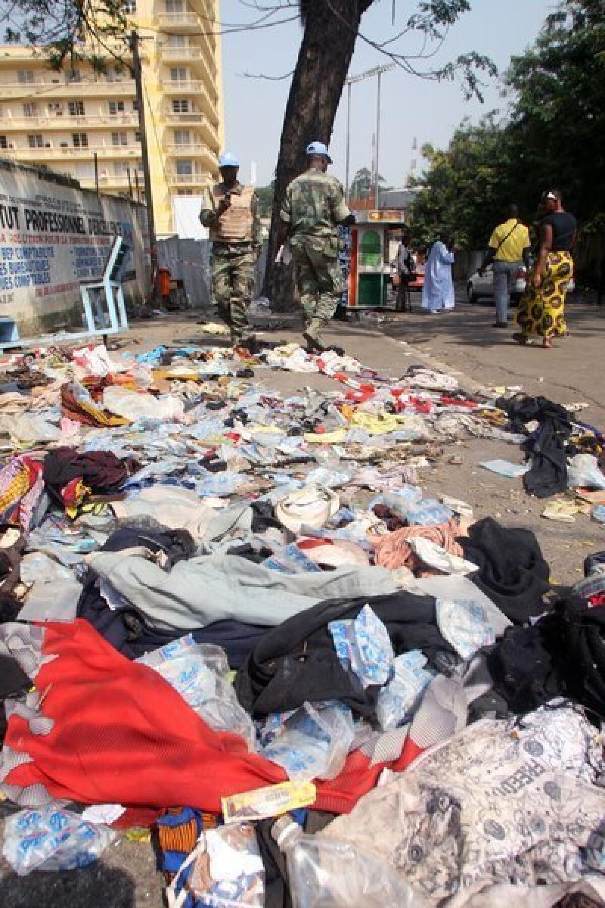 U.N. peacekeepers stand next to shoes and other items lying on the pavement at the scene of a stampede in Abidjan, Ivory Coast, on Tuesday.